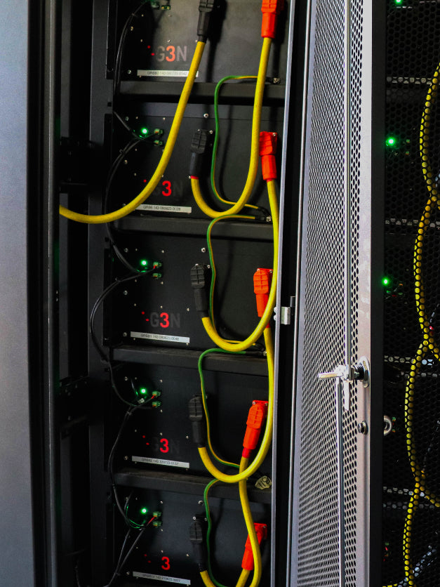 Close-up of I-G3N battery storage system in a server rack with visible power connections and operational status lights, showcasing advanced energy management technology.