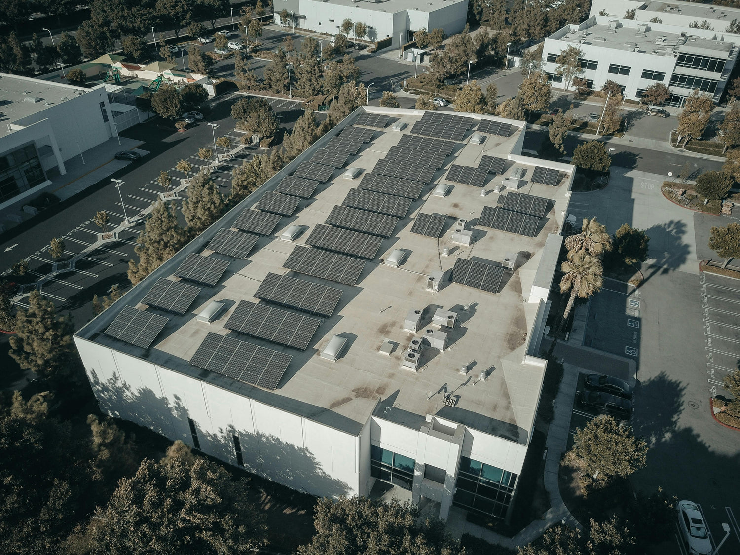 Aerial view of PV modules installed on a commercial building rooftop, showcasing a sustainable urban energy solution with rows of solar panels.