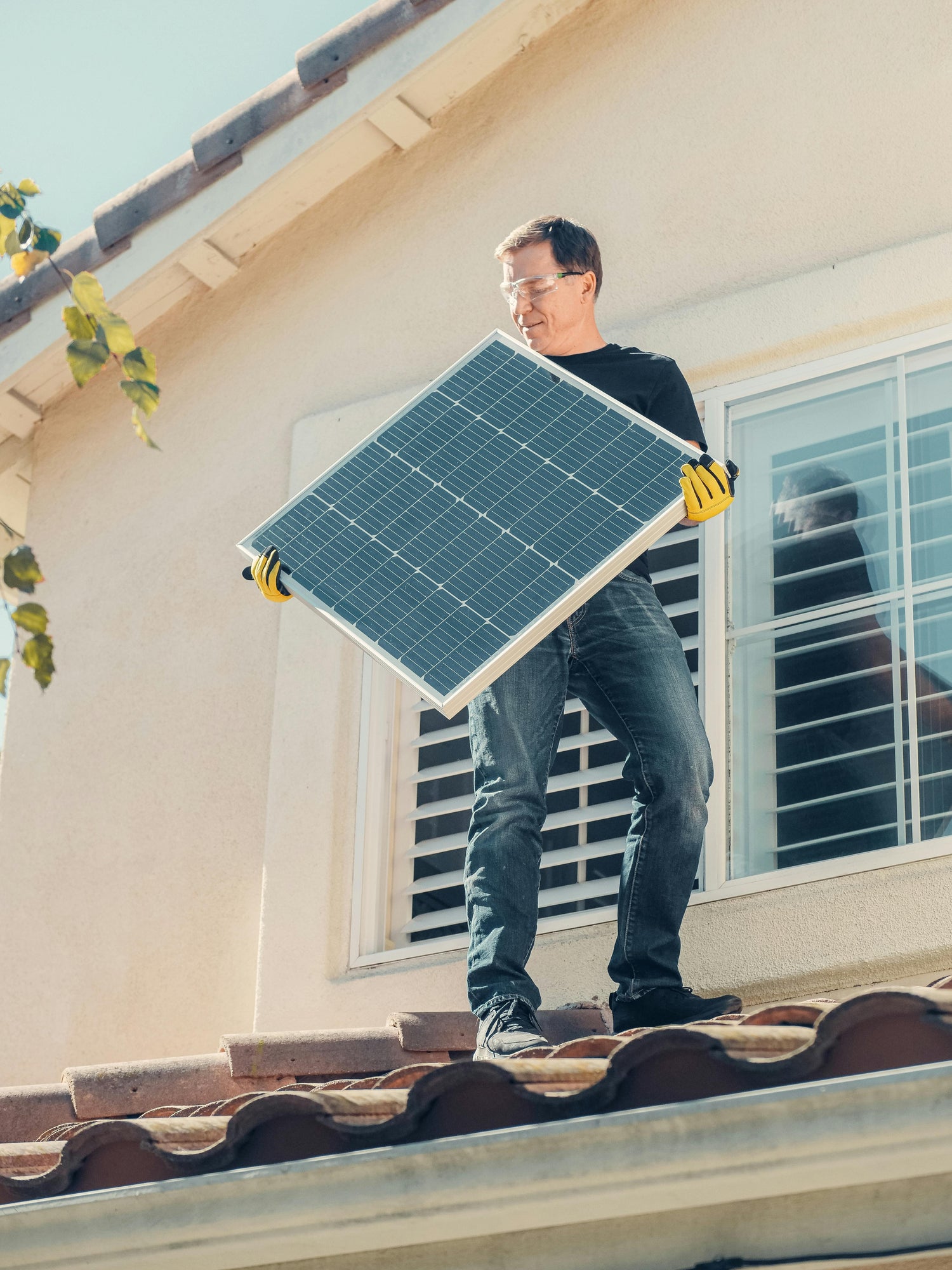 Man installing solar panel on a residential rooftop, demonstrating the use of high-quality n-type TOPCon PV modules for home solar energy solutions.