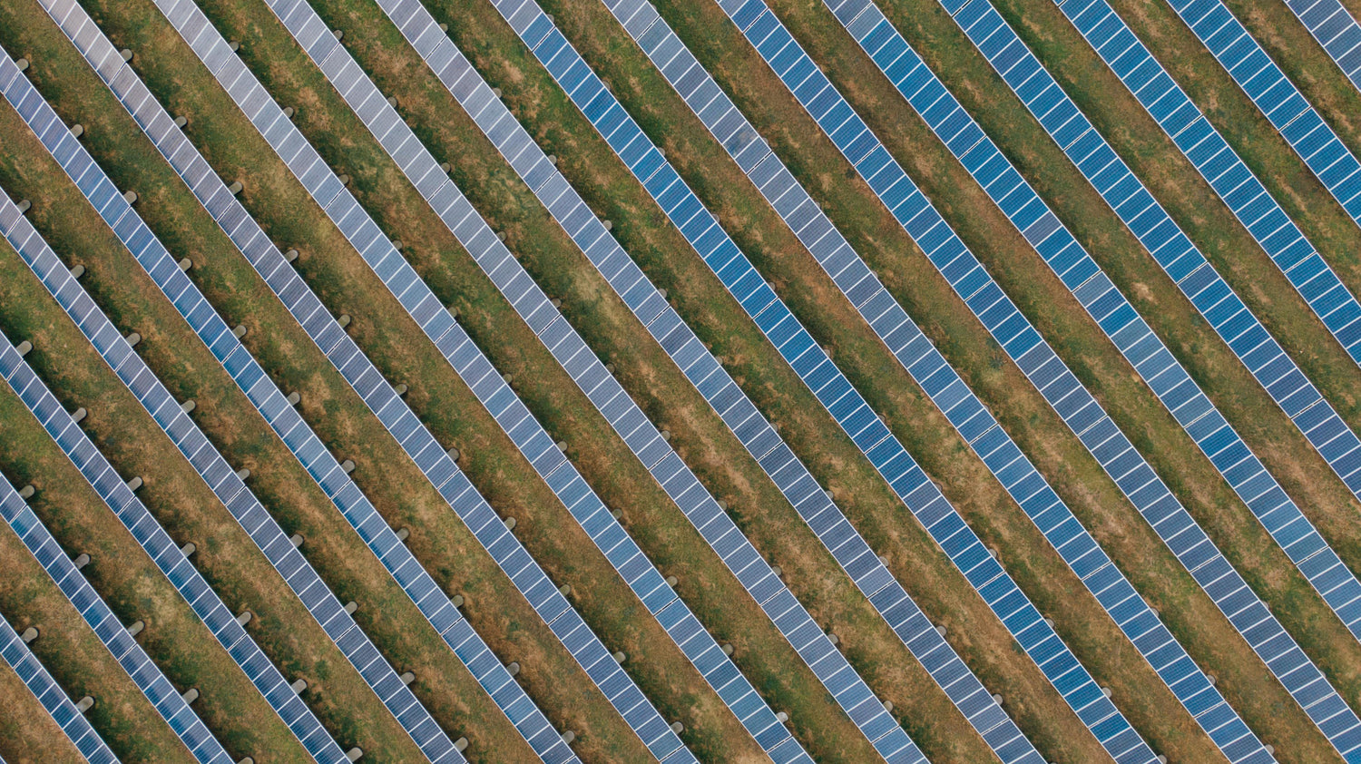 Aerial view of a vast solar farm, featuring neatly arranged rows of photovoltaic solar panels, demonstrating large-scale renewable energy production."