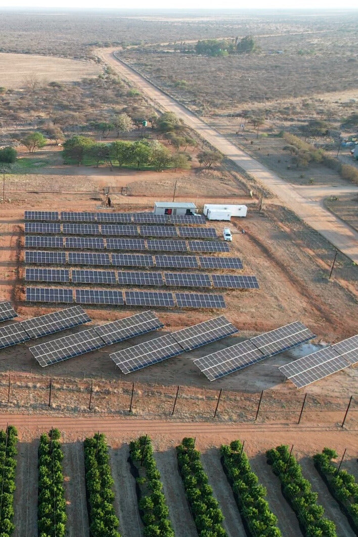 Aerial view of a solar farm equipped with ATESS inverters, strategically located in a rural setting alongside agriculture, demonstrating the integration of renewable energy and farming.